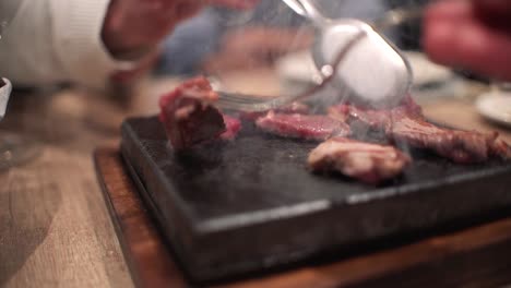 friends eating at restaurant celebrating birthday in dinning room, toasts, cheers and preparing their own meat at hot stone