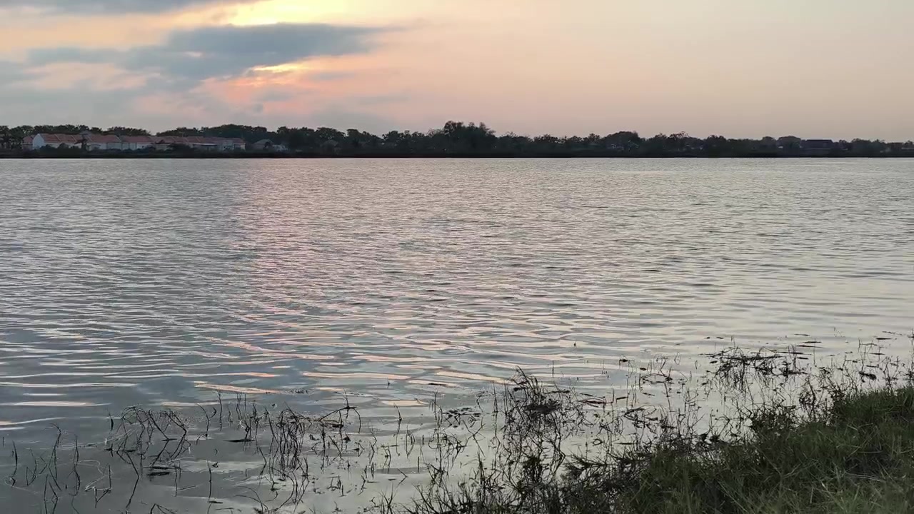 Lago calmo al tramonto con riva lontana