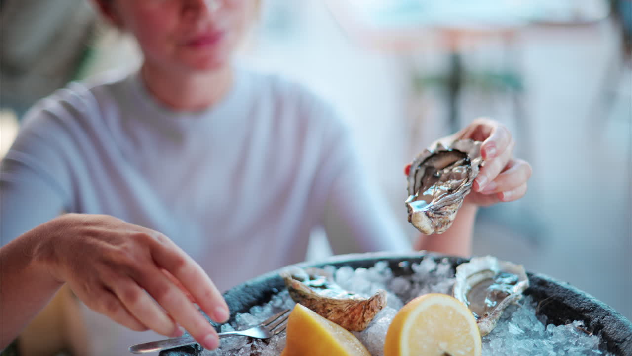 Woman squeezing lemon juice on a raw oyster at a restaurant