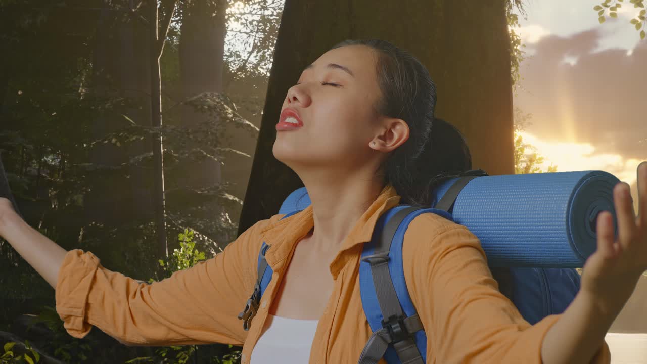 Close Up Side View Of Asian Female Hiker With Mountaineering Backpack Spreading Arms Enjoy Looking The View Around While Exploring Forest Nature