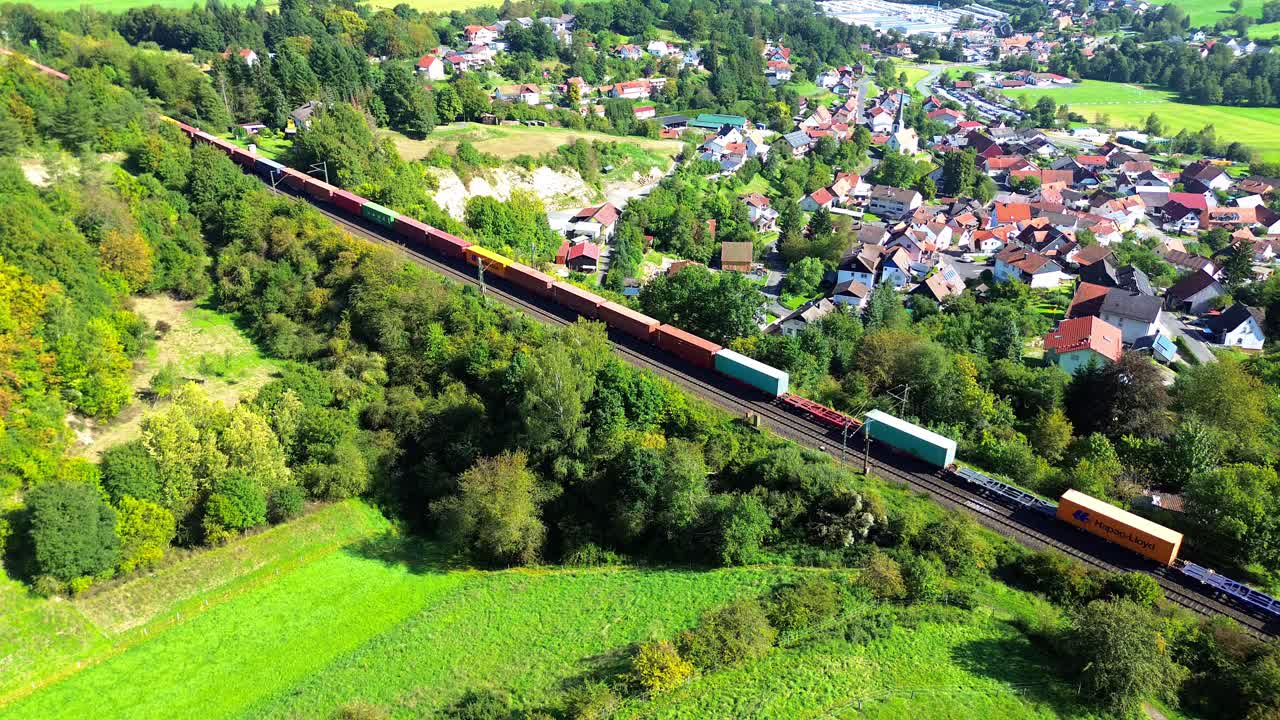 dron aéreo sobre un tren de mercancías que pasa por una aldea rural 4k