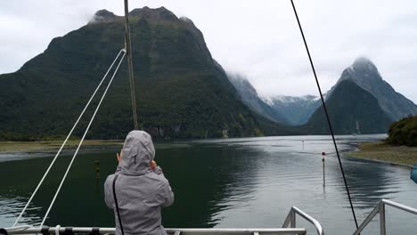person on a boat looking out at a majestic mountainous fjord
