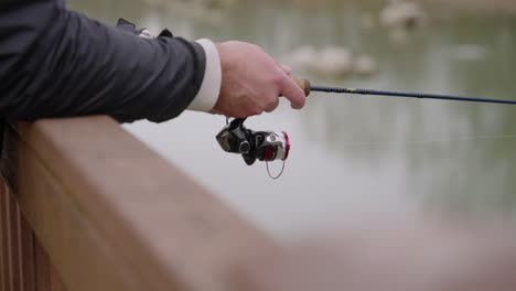 cinematic shot of a fisherman's hands holding a fishing rod over a fence