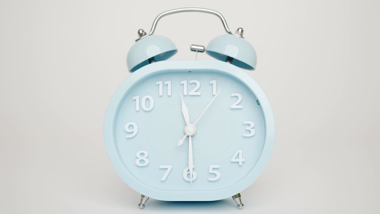 Close up, The blue alarm clock says twelve o'clock.