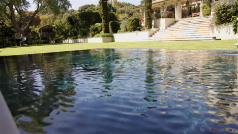 luxury home with beautiful garden and swimming pool reflecting sunlight