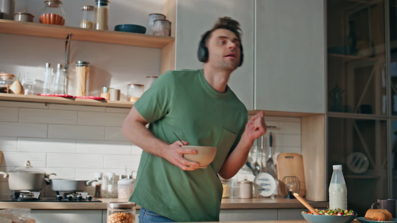 Funny guy cooking meal in earphones dancing kitchen closeup. Man listening music