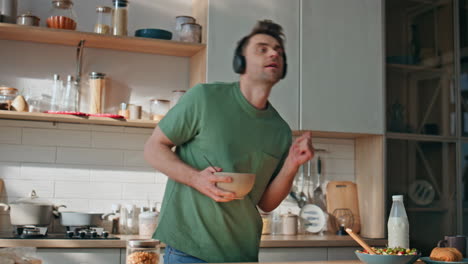 funny guy cooking meal in earphones dancing kitchen closeup. man listening music