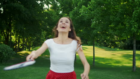 mujer jugando al bádminton en el prado. mujer enfocada mirando hacia arriba en el transbordador