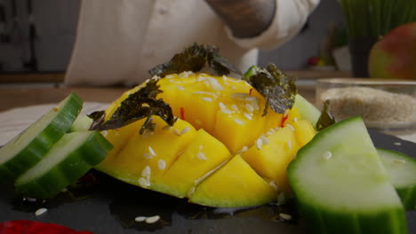 chef preparing a mango and cucumber salad with seaweed