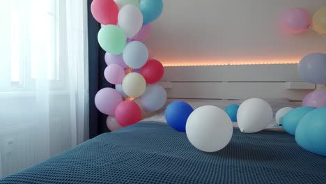 bed in bedroom decorated with colorful balloons, apartment bedroom interior. romantic date and holidays background.