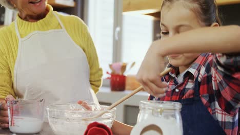 Little-girl-adding-flour-in-mixture-happy-grandma-holding-milk-jar-4K-4k