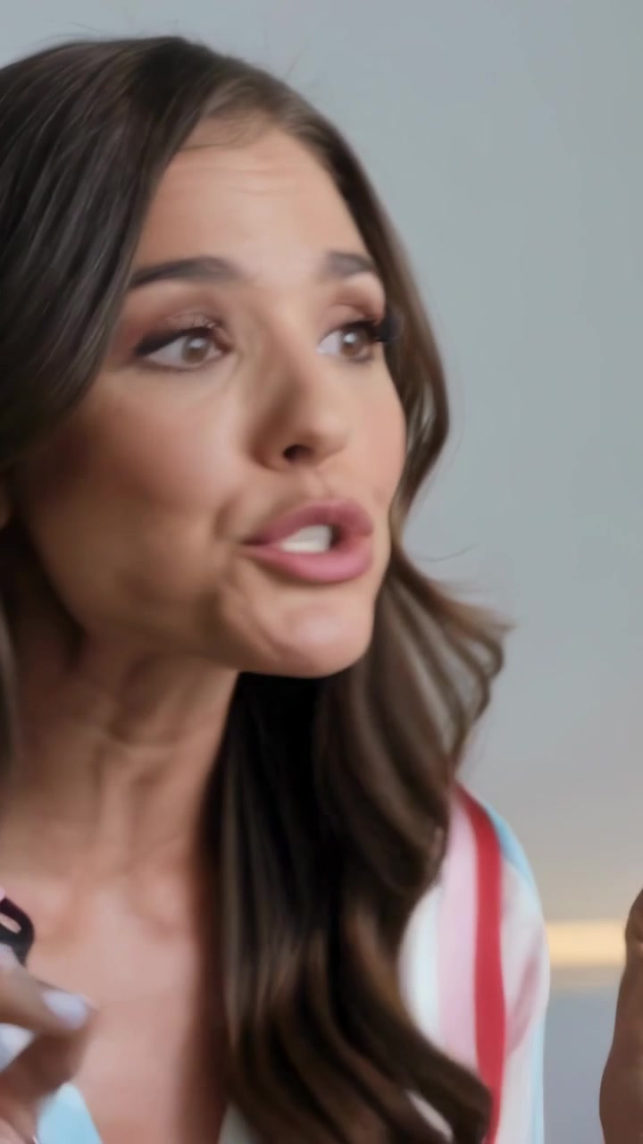 Vertical video: Answering offscreen cue, woman gesturing and speaking on set, striped top, lavalier
