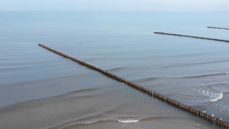 Aerial-shot-of-breakwater-and-sandy-beach-in-Ustka-in-winter