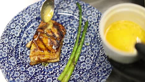 totoaba totuava fish dish being pour with melted butter in a restaurant kitchen by a chef