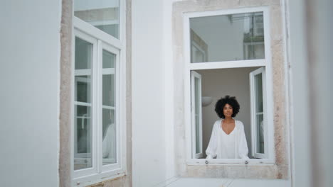 positive lady looking outdoors at window place. african woman watching cityscape
