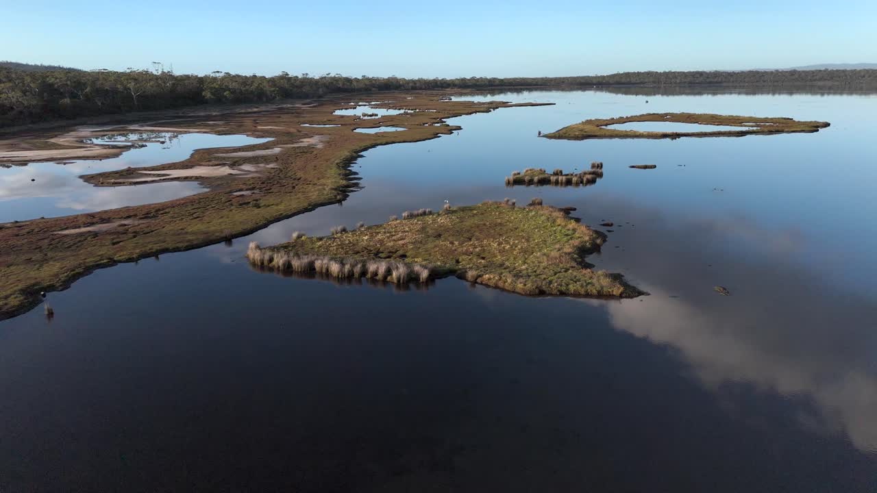 drone sobrevuela la reserva de caza de la laguna en coles bay, tasmania durante el amanecer dorado