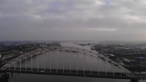 White car driving over a bascule bridge with on the background a barge across the Dutch river Noord. Drone pedestal shot