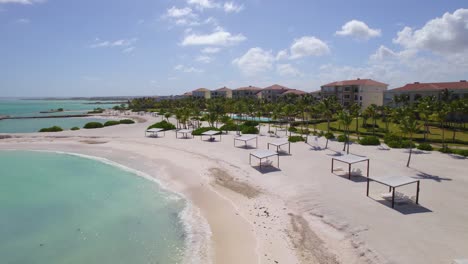 Flying-over-palm-trees-and-a-quiet-beach-with-no-people-in-Punta-cana,-Dominican-republic---aerial-view