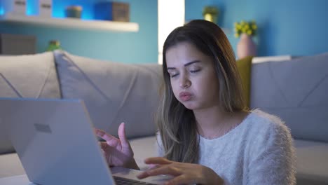 una joven infeliz y aburrida usando una computadora portátil.