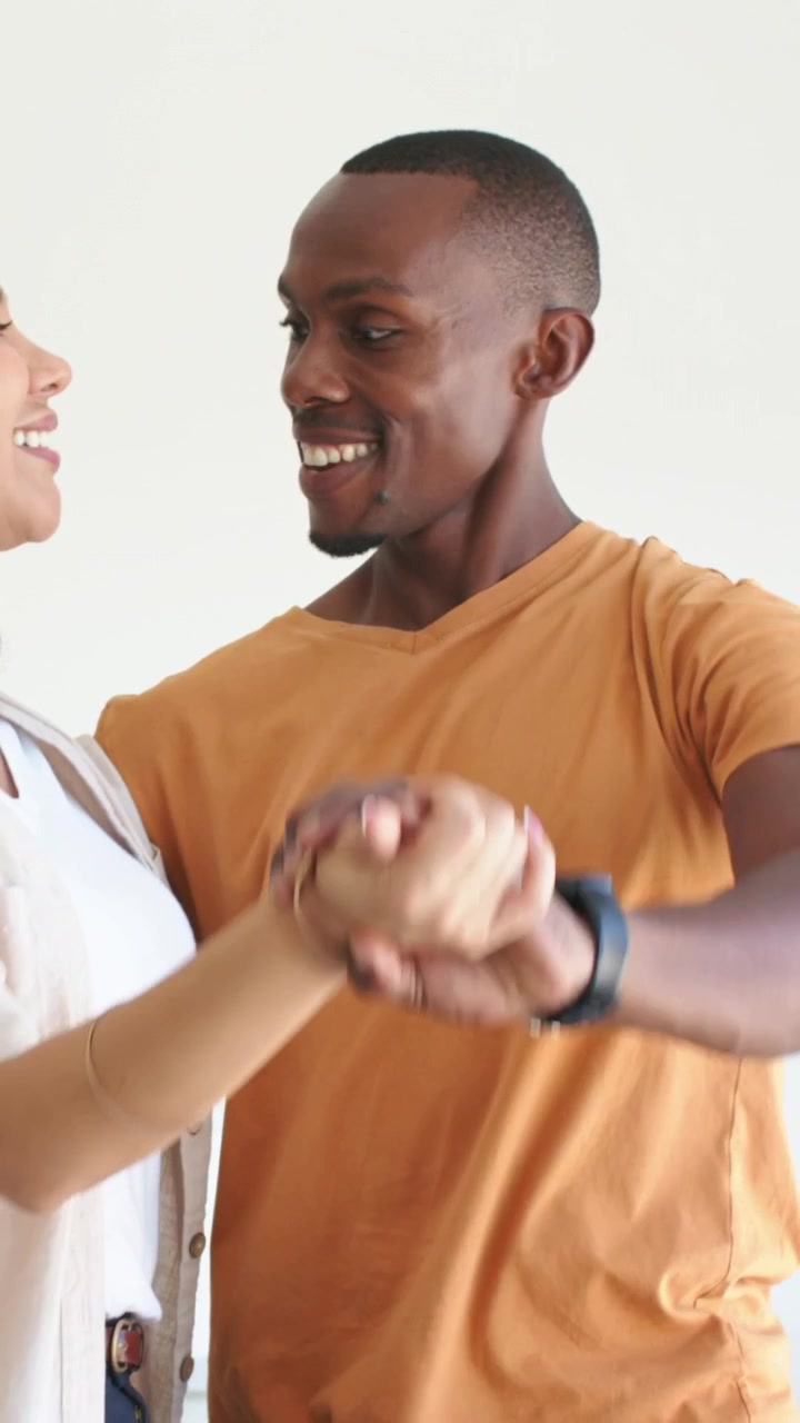 Couple laughing as man taking partner's hand and guiding twirl for marketing, smartwatch shown