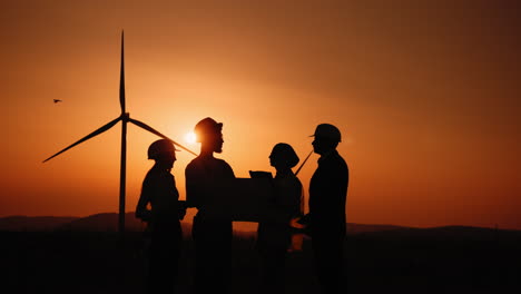 ingenieros de parques eólicos discutiendo el proyecto al atardecer