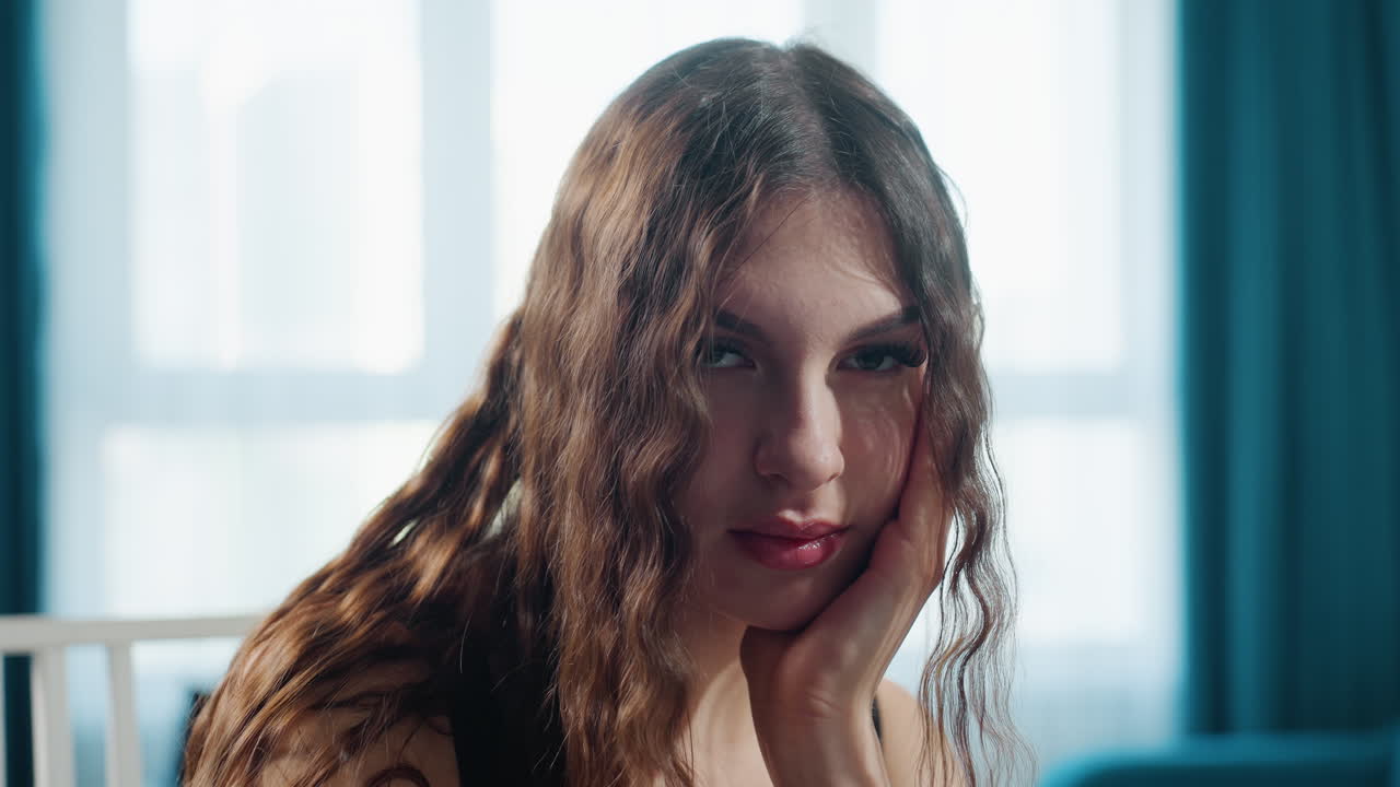 Pensive Woman By Window Light Staring Into Distance, Long Curly Hair Framed By Teal Curtain, Natural Backlight And Soft Morning Mood, Quiet Contemplative Pose For Editorial Portrait Session