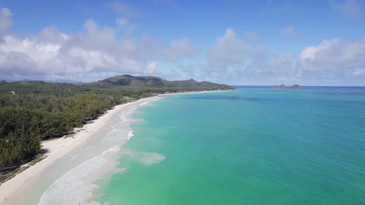 el agua turquesa se encuentra con la arena blanca y las montañas verdes exuberantes en este metraje de avión no tripulado del paraíso con cielo azul y nubes blancas hinchadas en la isla de oahu hawai
