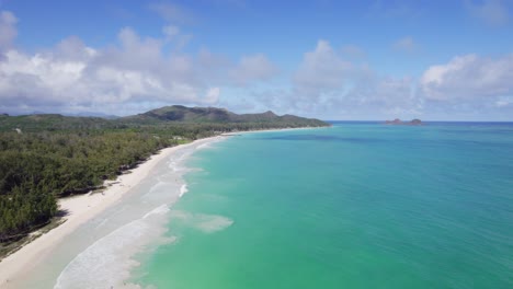 Türkisfarbenes-Wasser-Trifft-Auf-Weißen-Sand-Und-üppige-Grüne-Berge-In-Dieser-Drohnenaufnahme-Des-Paradieses-Mit-Blauem-Himmel-Und-Bauschigen-Weißen-Wolken-Auf-Der-Insel-Oahu,-Hawaii