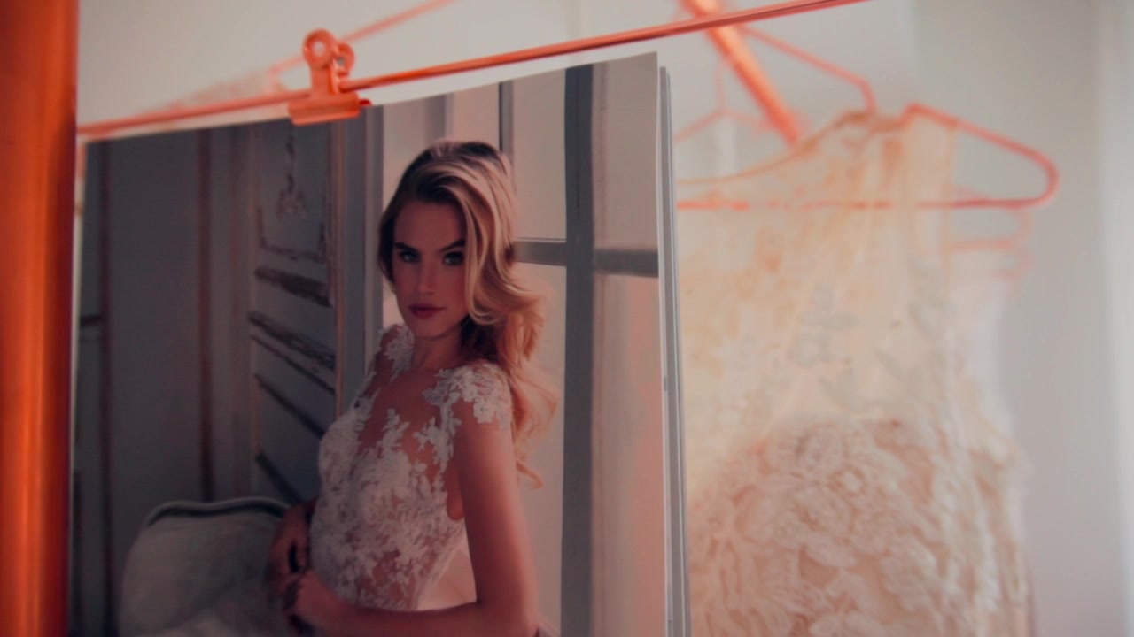 Wedding fashion magazine and bride white ivory dresses hanging on copper stand at store indoor. move away slowmotion