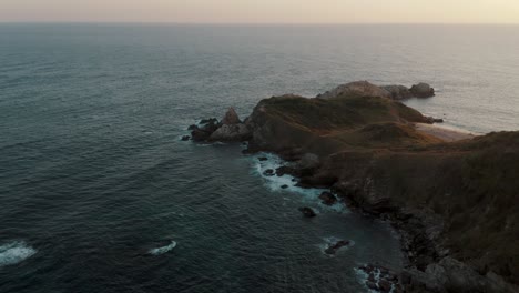 aerial orbit shot of famous cerro sagrado view point at shoreline with pacific ocean in backdrop during sunset in mexico