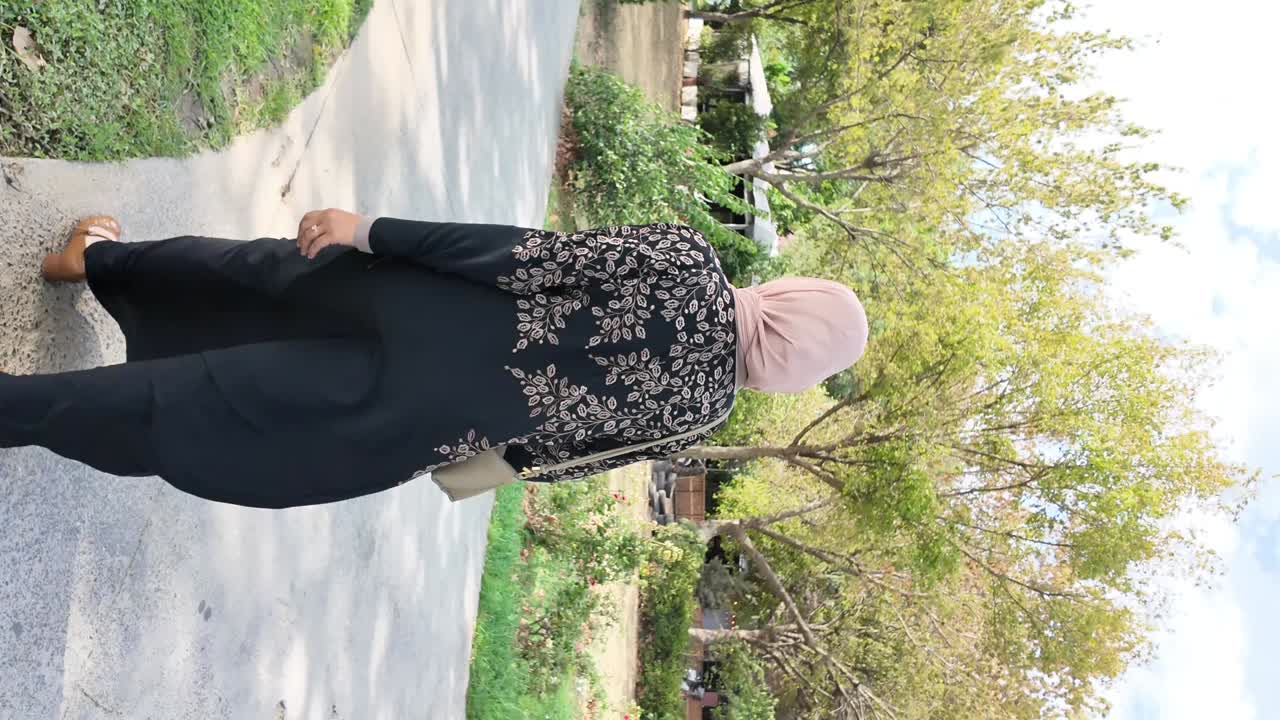 Woman in abaya walking on a sidewalk
