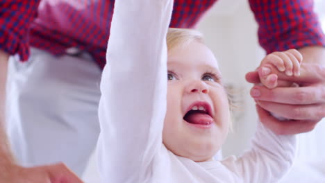 father helping daughter learn to walk at home, close up