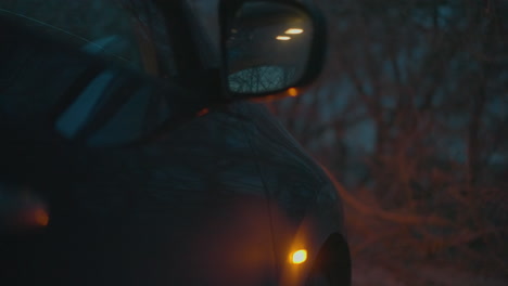 a close-up view of a car's side mirror and indicator light, illuminated in the dark