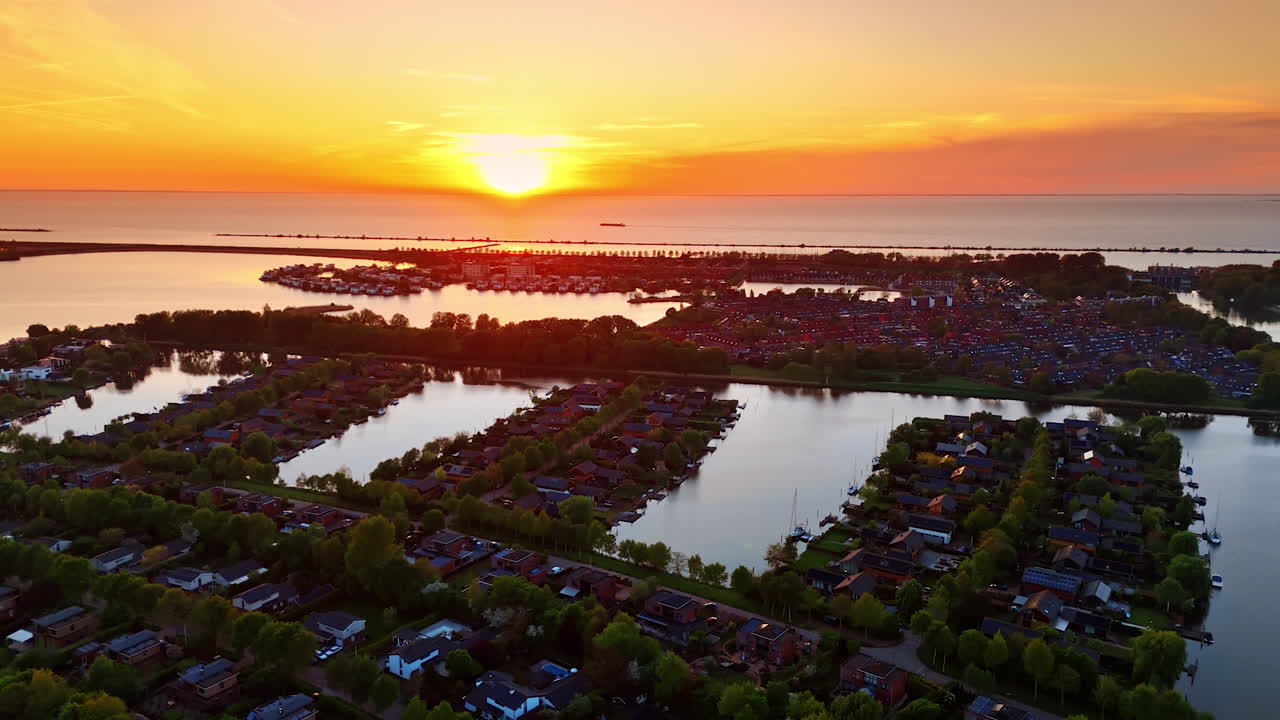 Flight over the picturesque village located on the water. Sun sets over the waterscape at backdrop. Vinkeveen, the Netherlands.