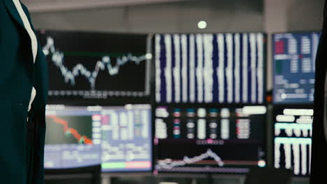 two businessmen shaking hands in front of stock market charts