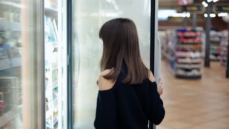 Independent-teenager-in-the-supermarket,-opens-freezer-door-and-take-and-ice-cream
