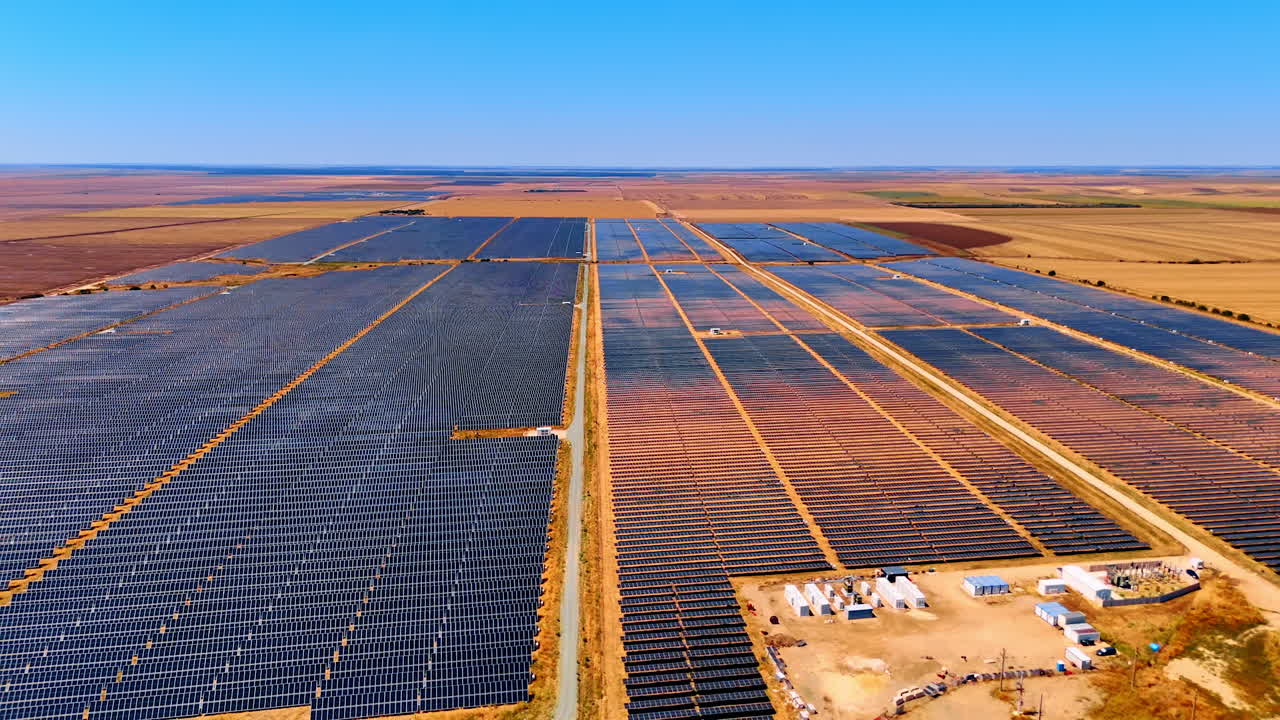 Expansive solar farm under clear skies. Vast solar panels stretch across the land, harnessing sunlight in a rural area during midday with blue skies