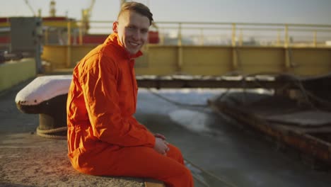 retrato de un joven trabajador en uniforme naranja sentado durante su descanso junto al mar