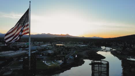 drone shot of the american flag soaring over bend, oregon at sunrise