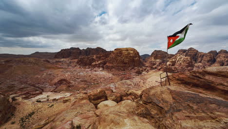 cinemagraph seamless video loop of the jordanian flag in petra, jordan, moving in the wind at a bedouin camp with vibrant colors and a view of the desert rocks with tombs carved into sandstone rock