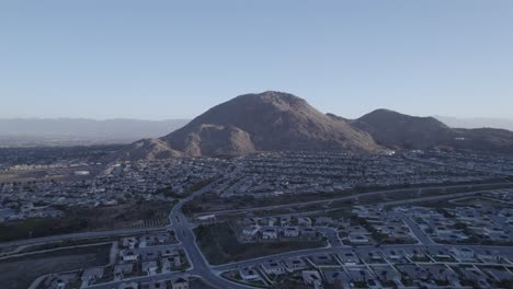 un fascinante vuelo de avión no tripulado entra en un vecindario, destacando las majestuosas montañas azules en el fondo, bañadas en el cálido sol de la mañana