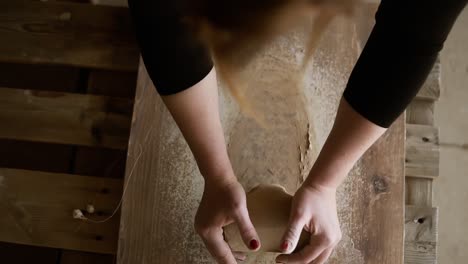 Top-Footage-Of-Female-Hands-With-Beautiful-Red-Manicure-Holding-Clay-And-Hardly-Kneading-It-On-A-Worktop