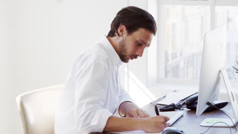 Hispanic-man-using-phone-and-computer-in-office,-close-up