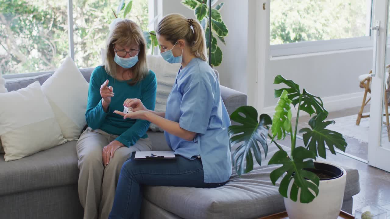 Female health worker showing medication doses to senior woman at home