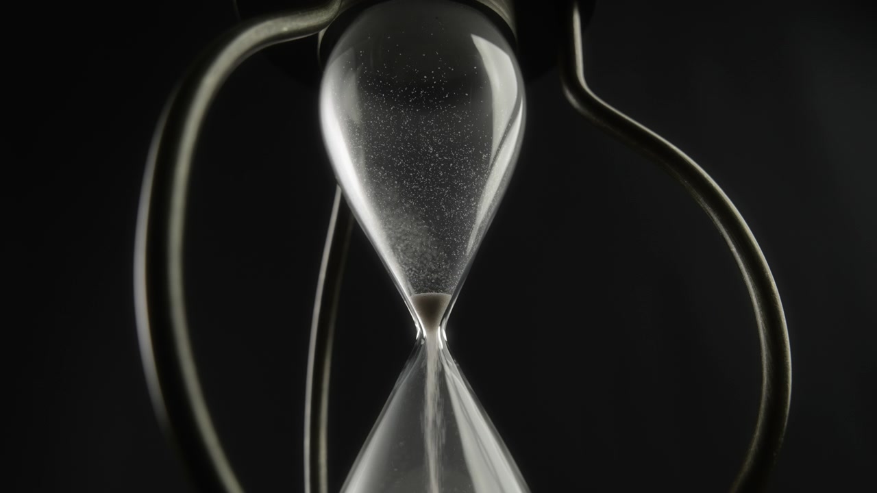 Hourglass Measuring Time with Sand Flowing Against Dark Background