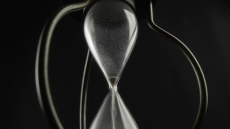 Hourglass Measuring Time with Sand Flowing Against Dark Background