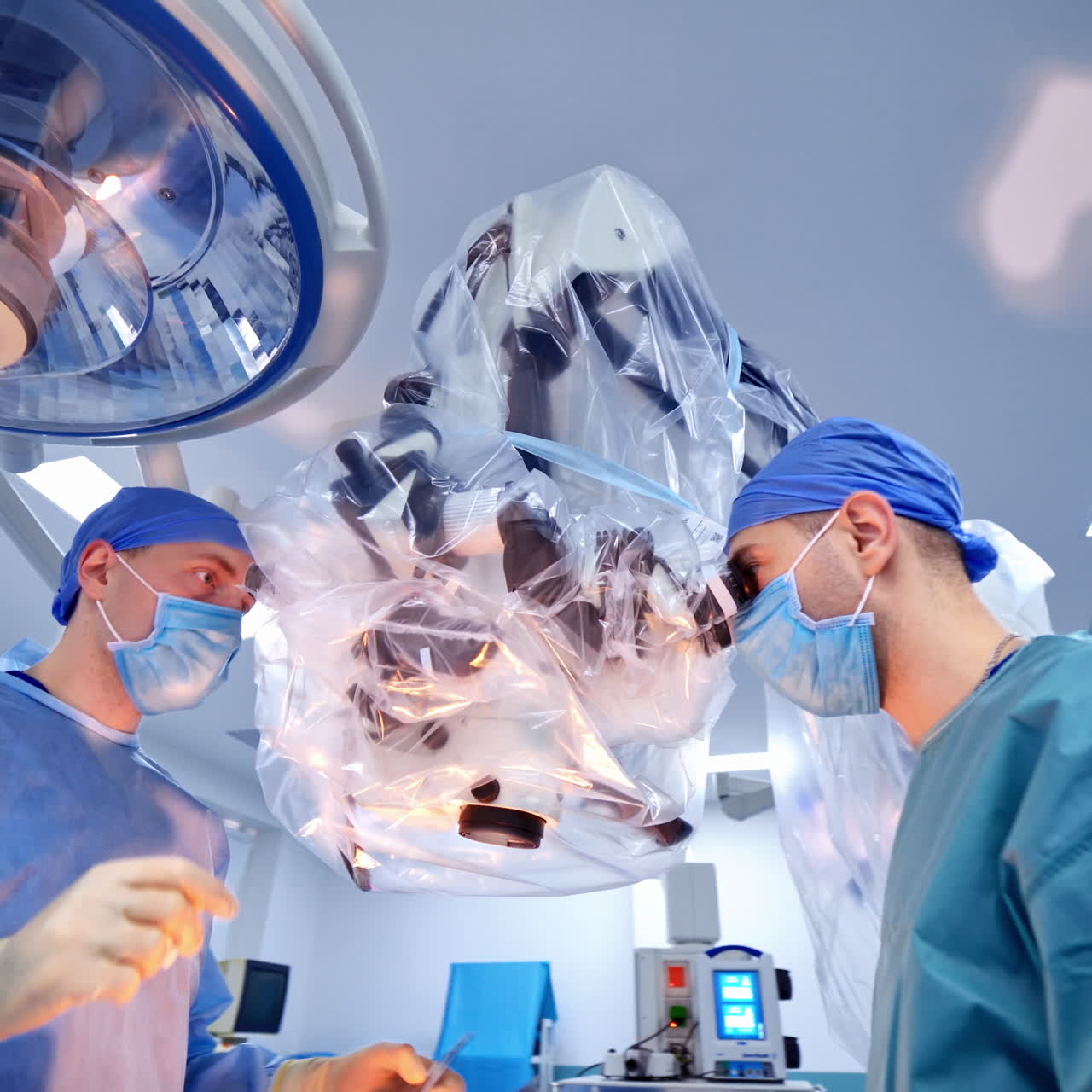 Two surgeons performing complicated surgery using modern equipment. Medical specialists making operation through the microscope. Healthcare.