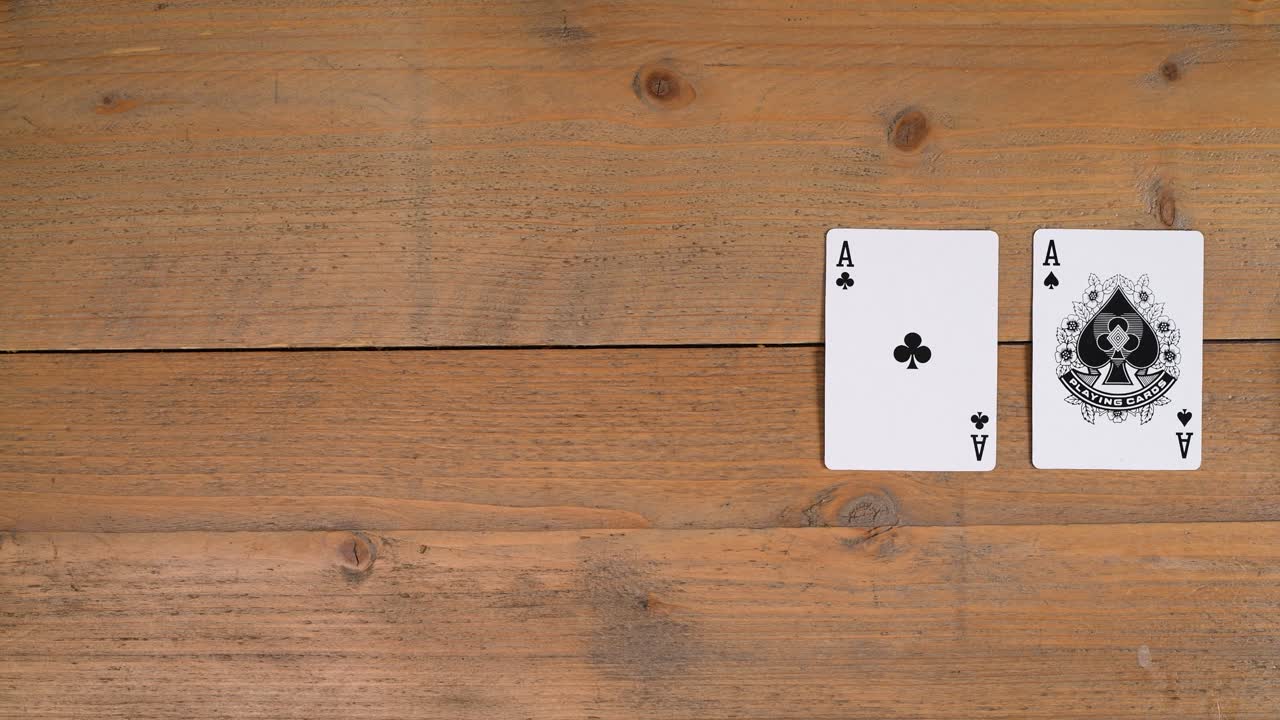 A person laying out a quads or four of a kind on a wooden table to educate the viewer on how to play poker