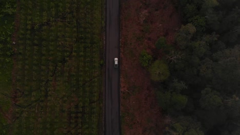 Ecuadorian-Countryside-Journey-from-an-Aerial-Drone-View-of-a-Vehicle-on-an-Isolated-Road-Amidst-Lush-Farmland-and-Verdant-Jungle