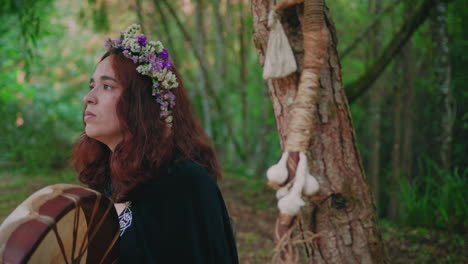 druid-girl-in-a-forest-playing-a-shamanic-drum-medium-close-shot